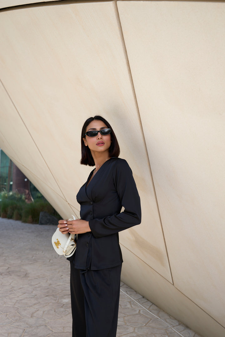 Woman in a black outfit standing against a modern architectural background
