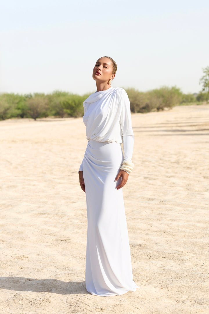 Woman in a white outfit standing in a desert landscape