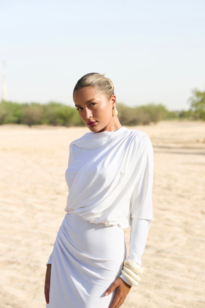 Woman in a white dress standing in a desert landscape