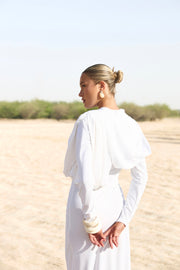 Woman in a white dress standing in a desert landscape
