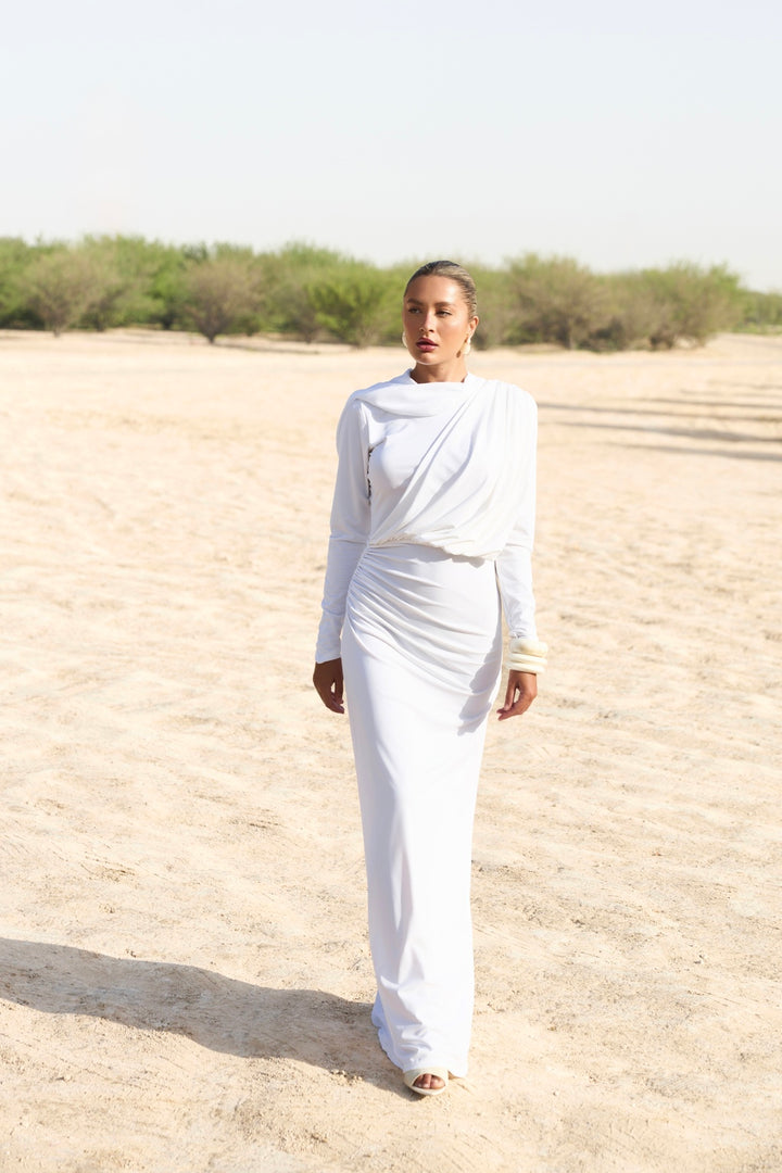 Person wearing a white outfit standing in a desert landscape
