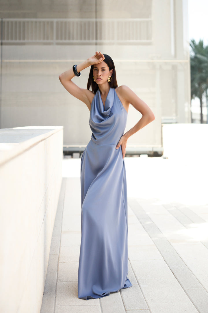 Woman in a long, light blue dress standing on a modern outdoor patio.
