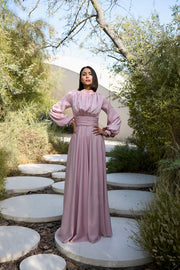 Woman in a pink dress standing on stone steps in a natural setting