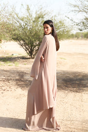 Woman in a long, light-colored dress standing in a desert landscape.