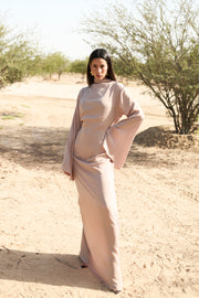 Woman in a long, light-colored dress standing in a desert landscape.