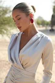 Woman wearing a light-colored dress with long sleeves in an outdoor setting