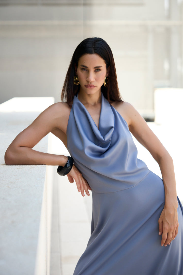 Woman in a light blue dress sitting on a white couch.