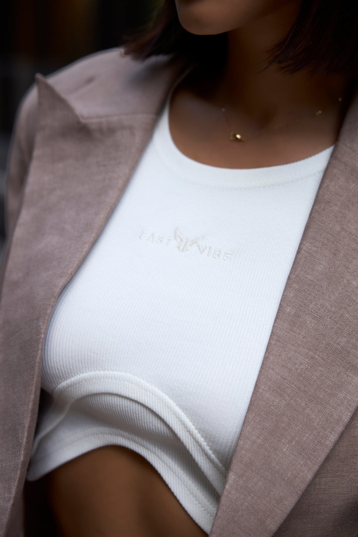 Person wearing a white top and brown blazer with a blurred background