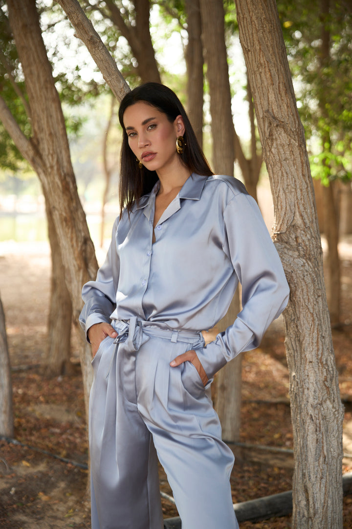 Woman in a light blue outfit standing in a forested area