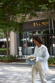 Woman reading a newspaper on a city street with a building in the background