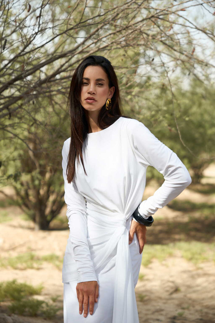 Woman in a white dress standing outdoors with trees in the background
