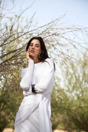 Woman in a white outfit standing outdoors with trees in the background