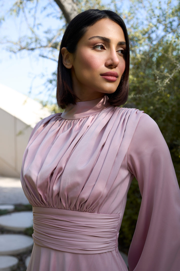 Woman wearing a pink dress standing outdoors with trees in the background