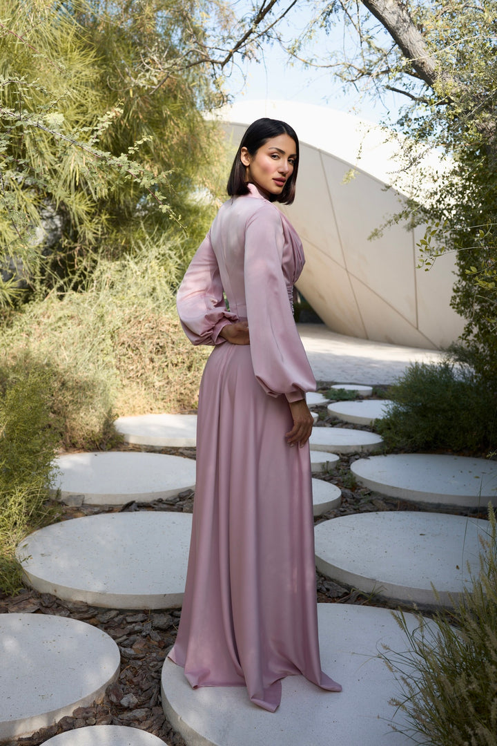 Woman in a pink dress standing on circular stone paths with greenery around.