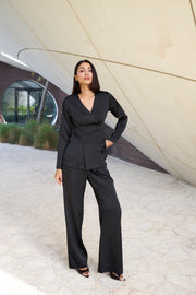 Woman in a black outfit standing in front of a modern architectural structure.