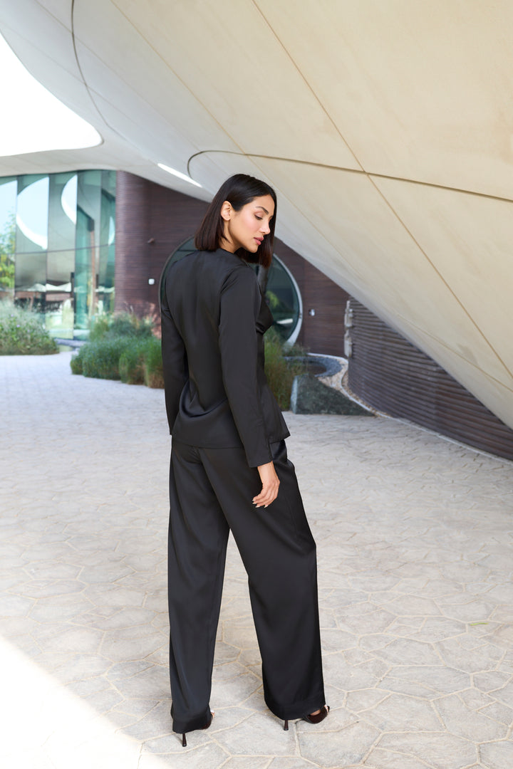 Woman in a black outfit standing in front of modern architectural structures.