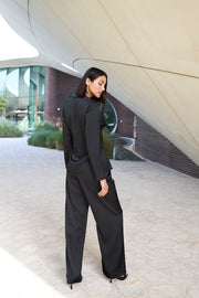 Woman in a black outfit standing in front of modern architectural structures.