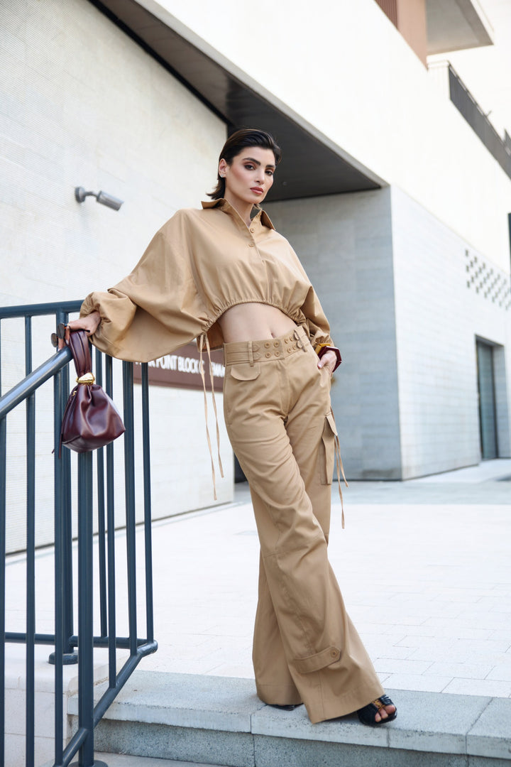 Woman in beige outfit standing on a staircase with a modern building in the background