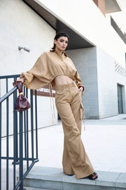 Woman in beige outfit standing on a staircase with a modern building in the background