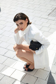 Woman in a white outfit squatting on a tiled pavement