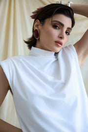 Woman wearing a white sleeveless top with a plain background