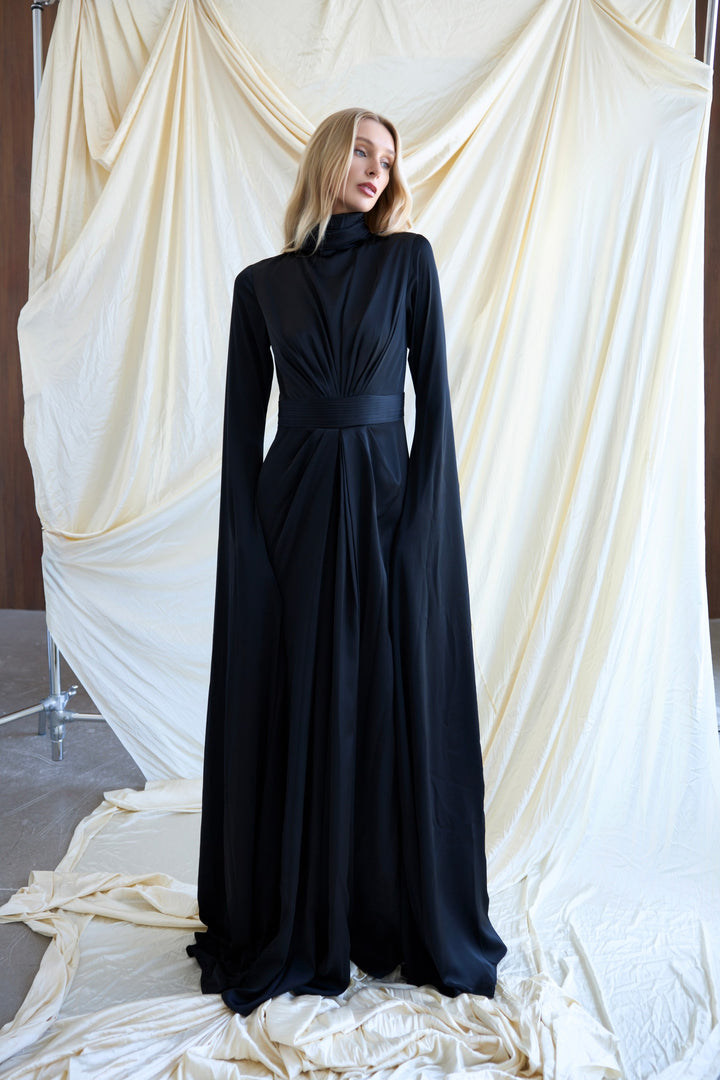 Woman wearing a black dress standing in front of white draped fabric
