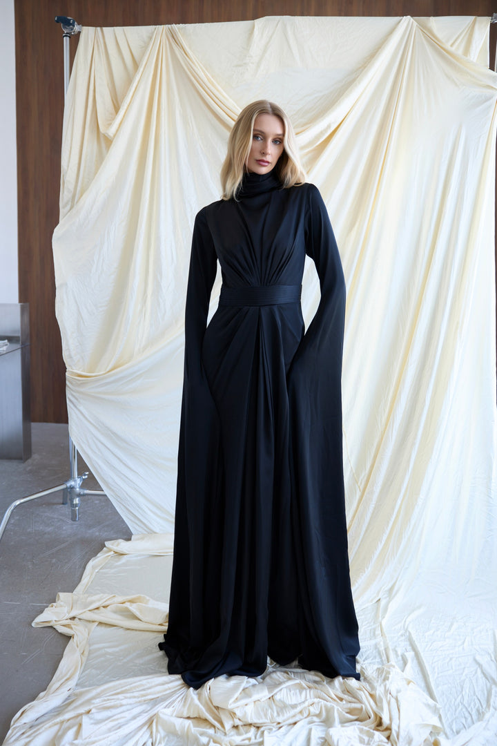 Woman wearing a black dress standing in front of draped white fabric
