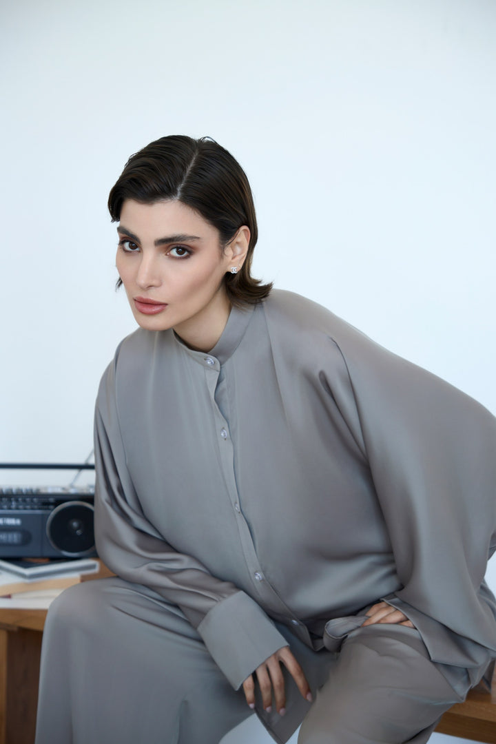 Woman wearing a gray outfit sitting on a white background