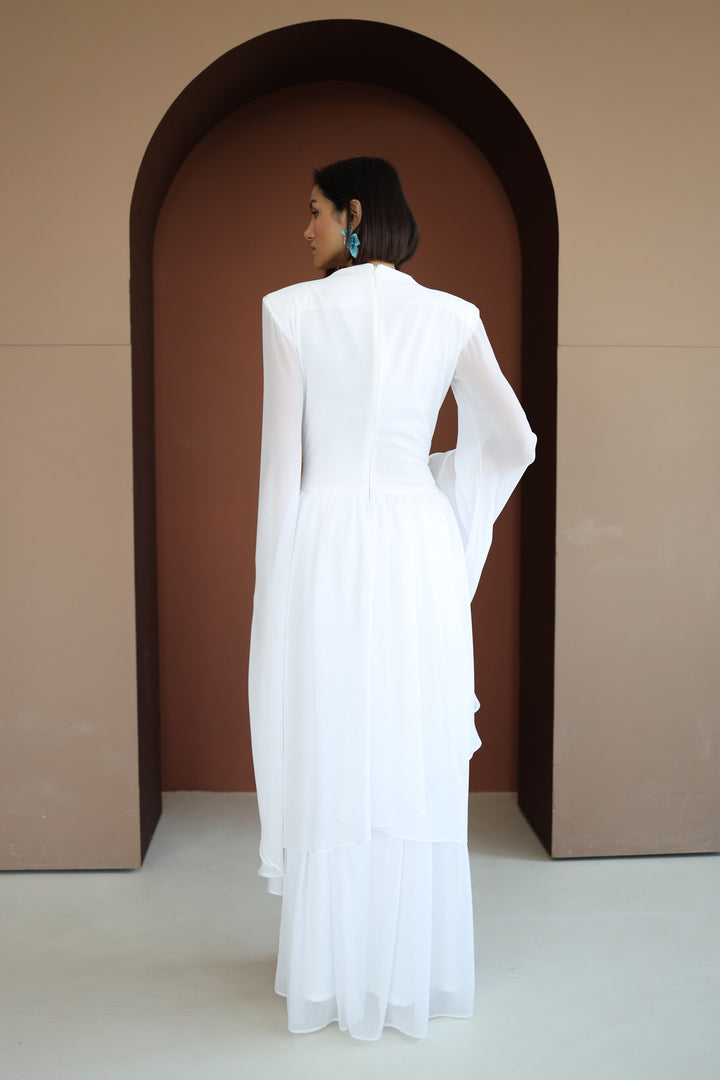 Woman in a white dress standing in front of an arched doorway.