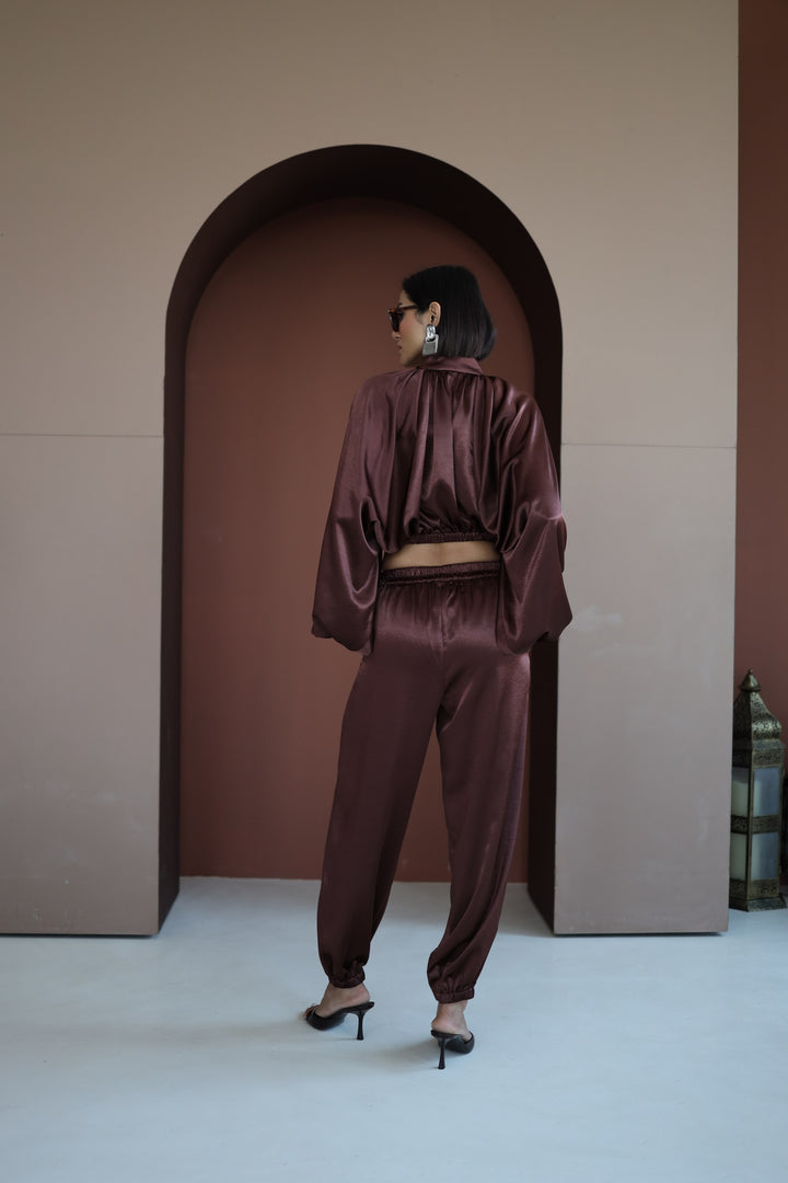 Person wearing a satin outfit standing in front of an archway.
