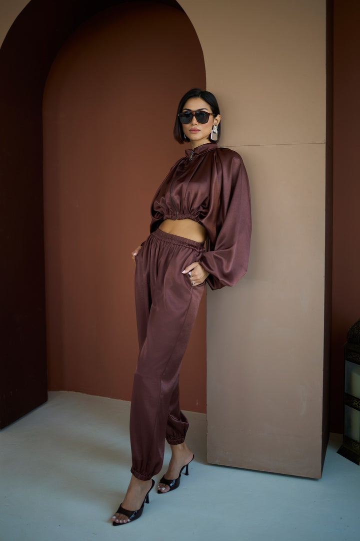 Woman in a satin outfit standing against a wall with a brown archway.