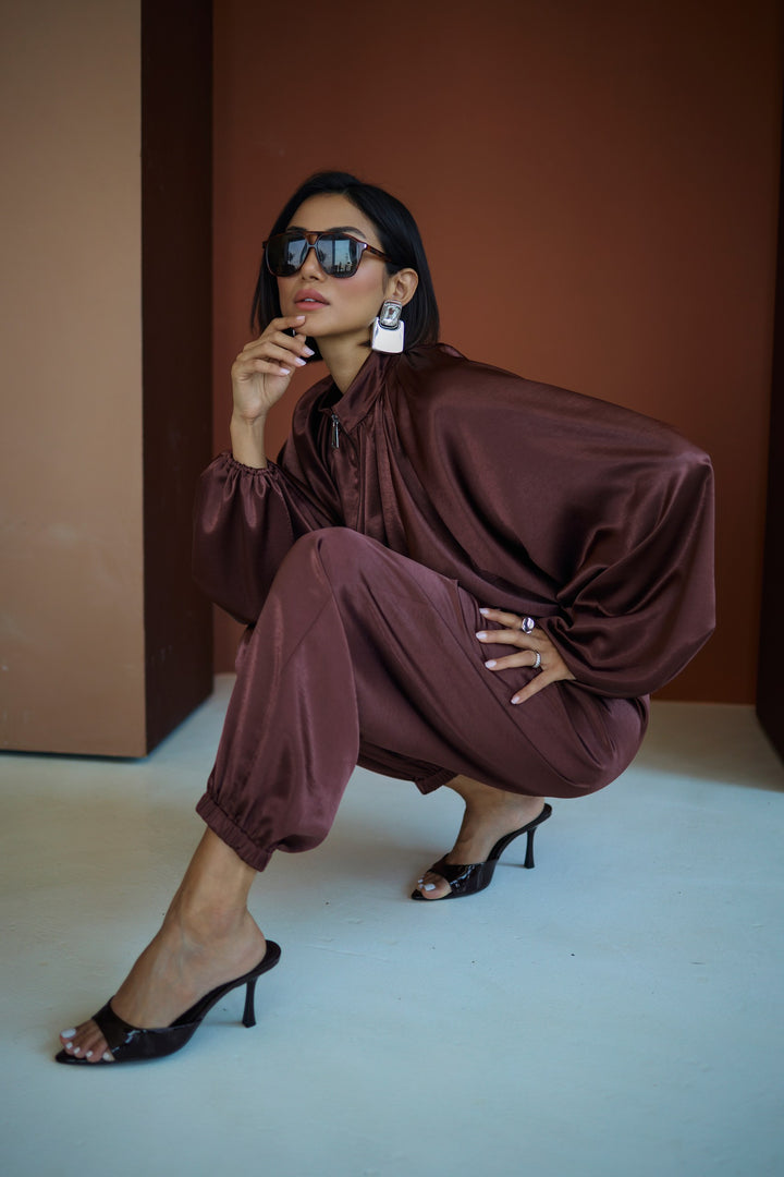 Woman in a brown outfit posing against a plain background
