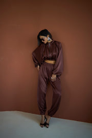 Woman wearing a brown satin outfit against a brown wall.