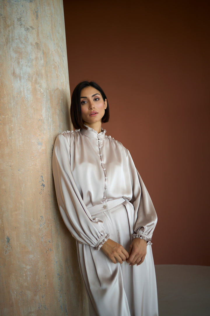 Woman wearing a light-colored dress against a textured wall.