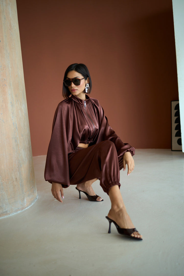 Woman in a brown outfit posing against a plain background