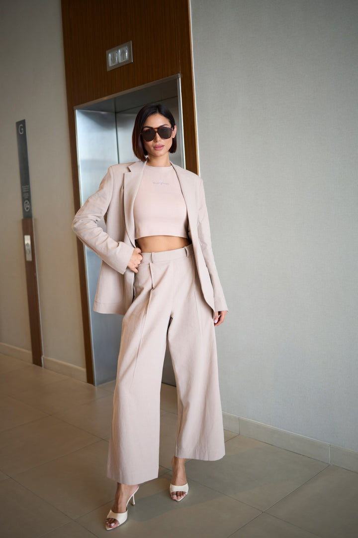 Woman in a beige outfit standing in an elevator shaft.