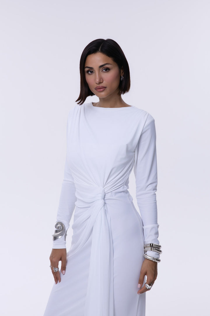 Woman wearing a white dress with long sleeves on a light gray background