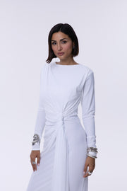Woman wearing a white dress with long sleeves on a light gray background