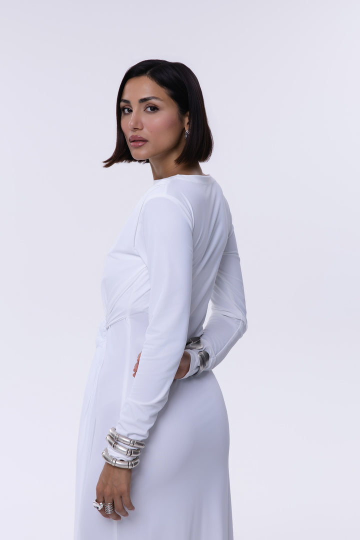 Woman wearing a white outfit with long sleeves and a belt on a white background