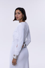 Woman wearing a white outfit with long sleeves and a belt on a white background