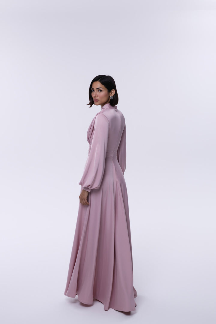 Woman wearing a long pink dress against a white background
