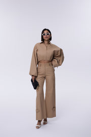 Person wearing a beige outfit with wide-leg pants on a white background