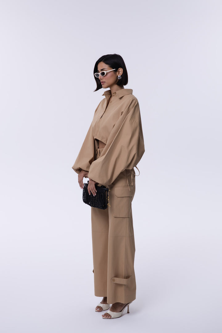 Woman wearing a beige trench coat and pants on a white background