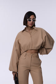 Woman wearing a beige outfit with sunglasses on a white background