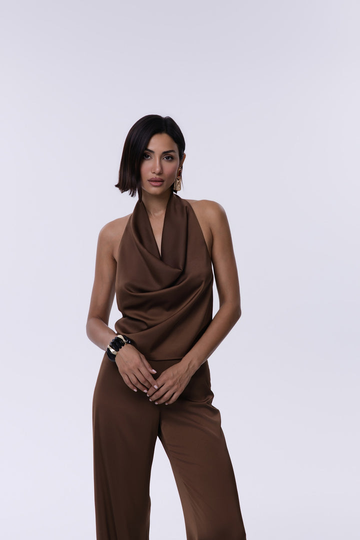 Woman wearing a brown sleeveless top and pants on a white background