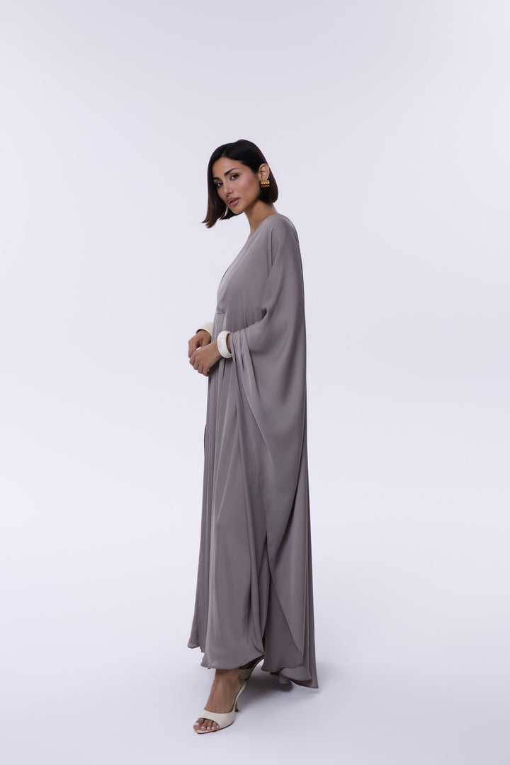 Woman wearing a long, light gray dress on a white background