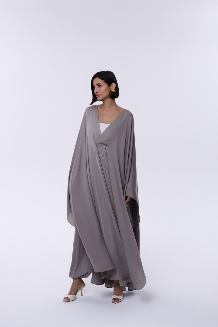 Woman wearing a gray flowing dress on a white background