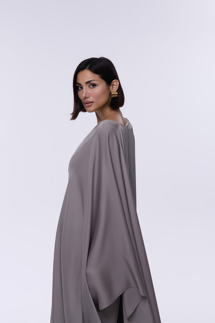 Woman wearing a gray poncho against a white background