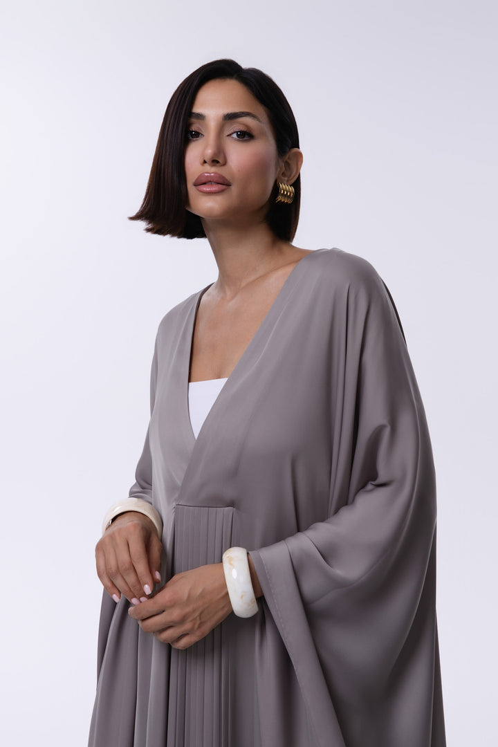 Woman wearing a gray abaya with a white top on a white background