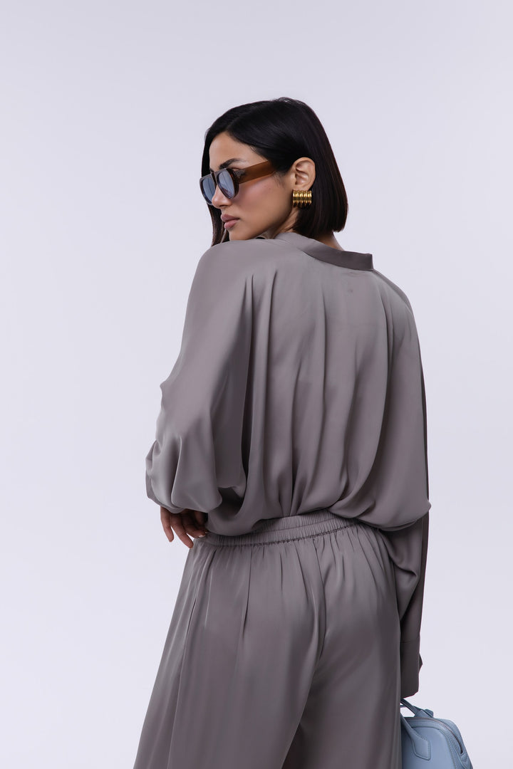 Woman wearing a gray outfit with sunglasses and a handbag on a white background